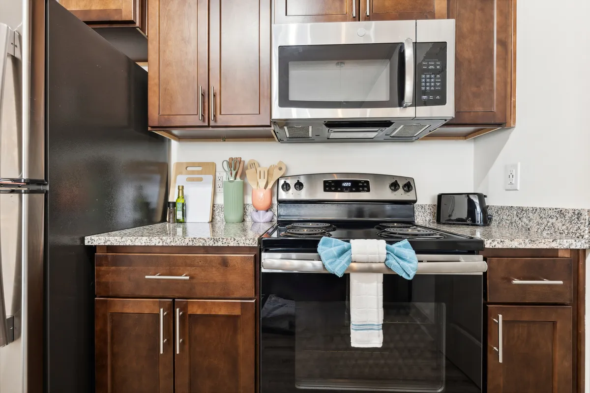 The photo focuses on a fully equipped kitchen with prominent stainless steel appliances and granite countertops. Colorful kitchen utensils add a lively touch, emphasizing the space's readiness for meal preparation and entertaining.
