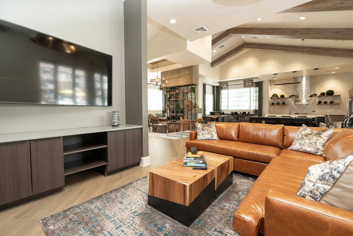 This cozy living room features a leather sectional sofa, wooden coffee table, large television, and decorative pillows. The setting is perfect for movie nights, intimate conversations, or enjoying quiet moments, emphasizing comfort and luxury.