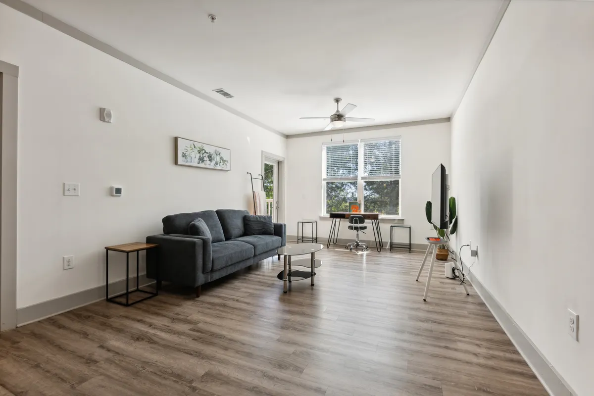 An inviting living area is depicted, featuring a cozy sofa, modern coffee table, and a large window that floods the space with natural light. A TV provides entertainment options, while the arrangement of furniture creates a comfortable and private atmosphere, ideal for relaxing after city adventures.