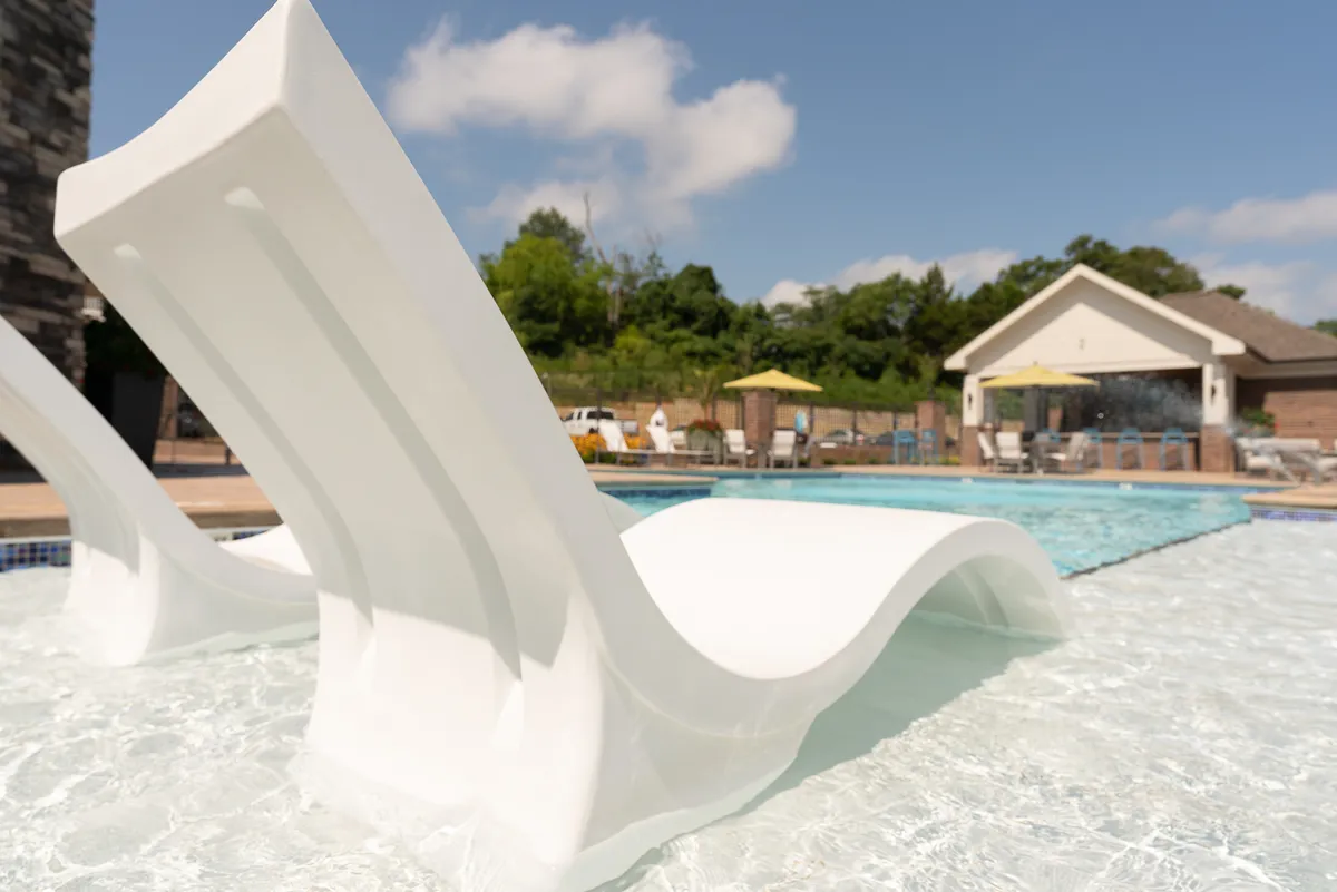 A serene pool area is featured, with inviting lounge chairs arranged for sunbathing, surrounded by lush greenery. The space offers both privacy and community, ideal for couples seeking a quiet, romantic setting or a refreshing dip together.